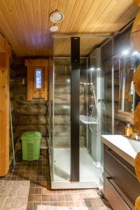 a shower with a glass door in a bathroom at Kuukkeli Log Houses Villa Aurora "Pupula" in Saariselka