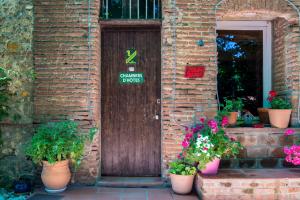 une porte avec des pots de fleurs devant un bâtiment dans l'établissement Domaine du Mas Bazan, à Alénya