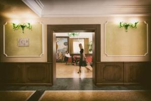 a woman walking through a hallway in a building at Artemis Hotel in Cefalù +37 photos