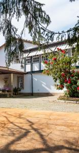 Biały dom z czerwonymi kwiatami przed nim w obiekcie Quinta de Mourães Casa dos Rododendros w mieście Lever