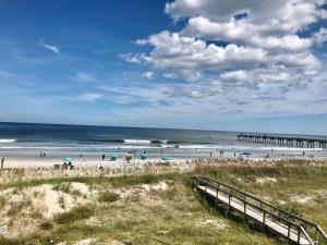 a beach with people on the sand and a pier at Casa Marina Hotel & Restaurant - Jacksonville Beach in Jacksonville Beach