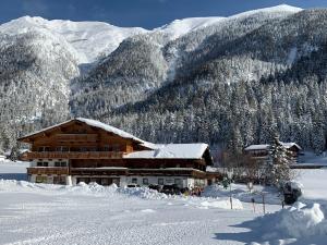 uma cabana de madeira na neve com montanhas em Lechnerhof Hotel-Garni em Achenkirch