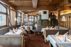 ein Restaurant mit weißen Tischen und Stühlen und Fenstern in der Unterkunft Alter Hof in Vaterstetten