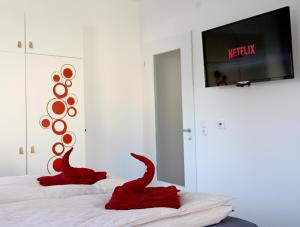 dois dinossauros vermelhos sentados numa cama com uma televisão em Gemütliches Appartement mit Netflix, Nespresso und Boxspringbett em Augsburg