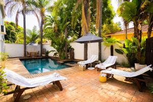 a backyard with a pool and chairs and an umbrella at Village Ridge Boutique Stays in Pretoria