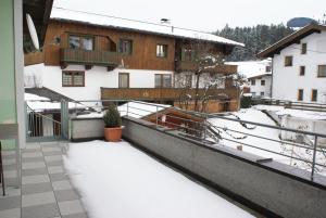 un balcon enneigé d'une maison avec de la neige au sol dans l'établissement Haus Schiwelt, à Kirchberg in Tirol