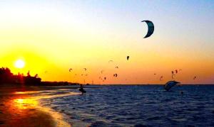 un grupo de personas volando cometas en la playa al atardecer en Vila Ybytu Eco Resort, en Itarema