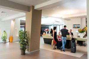 2 personnes debout dans un hall avec bagages dans l'établissement Saracen Sands Hotel & Congress Centre - Palermo, à Isola delle Femmine