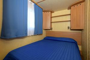 a bedroom with a blue bed and a window at Camping Village Tuscia Tirrenica in Tarquinia