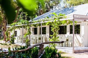 Casa blanca con sillas y árboles blancos en Addo African Home, en Addo