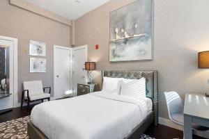 a bedroom with a large white bed and a desk at Bay Village Suites in Boston