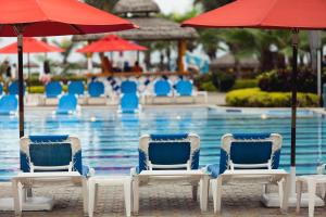 um grupo de cadeiras e guarda-sóis ao lado de uma piscina em Royal Decameron Punta Centinela - All Inclusive em Ballenita