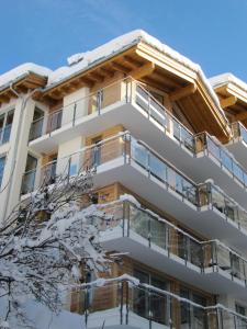 a building with snow covered trees in front of it at Hörnligrat Apartments in Zermatt
