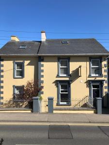 una casa amarilla al lado de una calle en Beach Haven Apartments, en Tramore