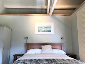 a bedroom with a bed and a picture on the wall at Coed y Berclas cottage, private orchard with stunning views in Llandegfan