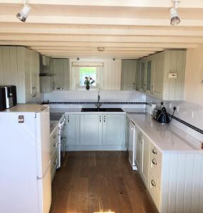 a large kitchen with white cabinets and a sink at Coed y Berclas cottage, private orchard with stunning views in Llandegfan