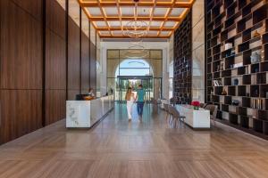 a lobby with a woman walking down a hallway at Aliathon Ionian in Paphos City +68 photos
