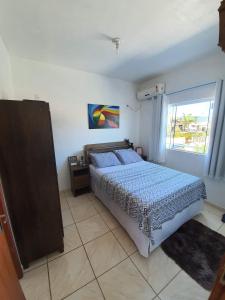 a bedroom with a bed and a large window at Apartamento próximo ao Aeroporto de Florianópolis. in Florianópolis