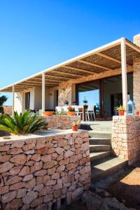 a stone wall in front of a house with a wooden roof at Casa Romero in Cala Saona