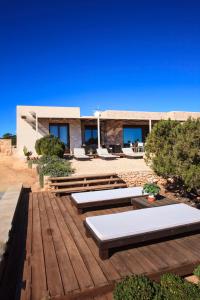 a wooden deck with benches and a house at Casa Romero in Cala Saona