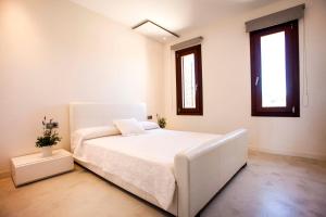 a white bedroom with a large white bed with two windows at Casa Romero in Cala Saona +35 photos