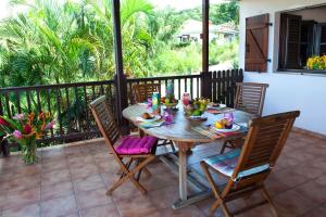 Rose phoenix appartement terrasse et piscine vue mer في لو أنسيه دو أرليتز: طاولة وكراسي خشبية على شرفة مع طاولة وكرسي