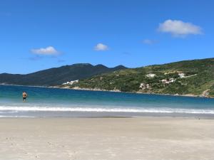 una persona caminando en una playa cerca del agua en Casa Acolhedora no Paraíso, en Arraial do Cabo