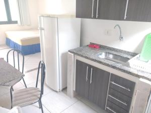 a kitchen with a refrigerator and a table and chairs at Chalés Marazul Toninhas in Ubatuba