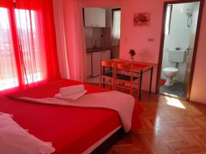 a bedroom with a red bed and a kitchen at Apartments Ana in Podstrana