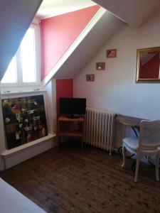 a attic room with a tv and a table and a window at La Chambre d'hôte de Chris in Cherbourg en Cotentin