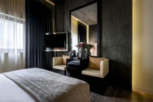 um quarto de hotel com uma cama, uma cadeira e um espelho em 9Hotel Mercy em Lisboa