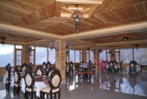 a dining room with a table and chairs and windows at Fairy Land Hotel in Hunza Valley