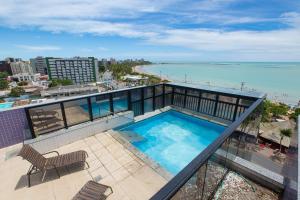 a balcony with a swimming pool and a view of the ocean at Flat Beira-Mar - NEO Pajuçara in Maceió