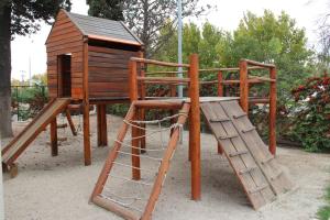 un parque infantil de madera con una casa de madera y una escalera en Motel A.C.A. Cipolletti en Cipolletti