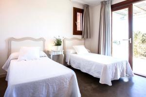 a bedroom with two beds with white sheets and a window at Casa Santolina in Cala Saona +41 photos