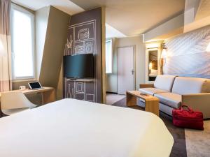 a hotel room with a couch, coffee table and a television at ibis Paris Gare du Nord Château Landon 10ème in Paris