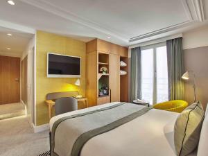 パリにあるMercure Paris Opera Garnier Hôtel & Spaのベッドとテレビが備わるホテルルームです。