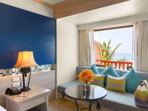 a living room with a blue couch and a table at Novotel Phuket Resort in Patong Beach