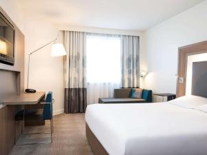a hotel room with a bed and a desk and a chair at Novotel Brussels City Centre in Brussels