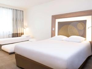 a hotel room with two beds and a window at Novotel Brussels City Centre in Brussels
