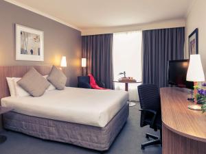 a hotel room with a bed and a desk at Mercure Sydney Parramatta in Sydney