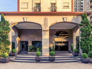 a building with two arched entrances with potted plants at Mercure Sao Paulo JK in São Paulo
