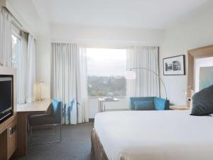 a hotel room with a bed and a television at Novotel Tainui Hamilton in Hamilton