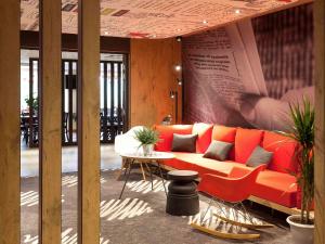 - un canapé orange dans une chambre avec une table dans l'établissement ibis Cherbourg La Glacerie, à Cherbourg en Cotentin