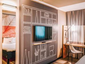 a room with a wall with a tv and a bed at ibis Hotel Frankfurt Airport in Kelsterbach