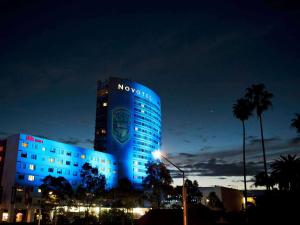 un edificio iluminado en luces azules por la noche en Novotel Sydney Olympic Park en Sídney