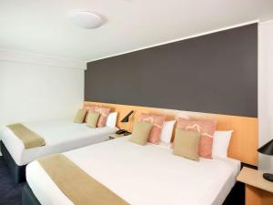 a hotel room with two beds with pink pillows at ibis Sydney World Square in Sydney