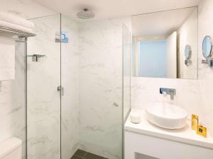 a white bathroom with a sink and a shower at ibis Sydney World Square in Sydney