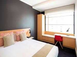 a bedroom with a bed and a desk and a window at ibis Sydney World Square in Sydney