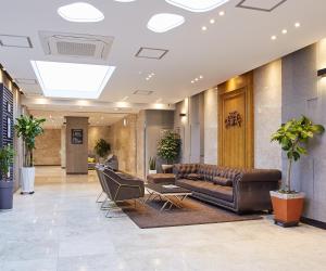 a lobby with a brown leather couch and chairs at Noble Stay Hotel in Gwangju